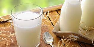 یک لیوان شیر در کنار دوبطری شیر